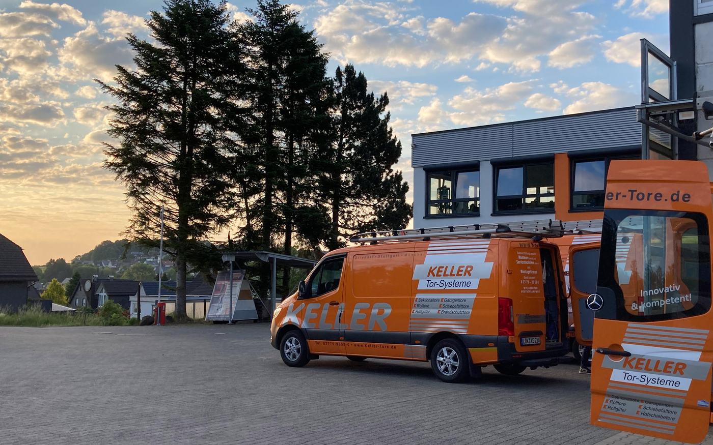 Montagefahrzeuge vor der Zentrale von Keller Tor-Systeme in Driedorf bei Sonnenuntergang